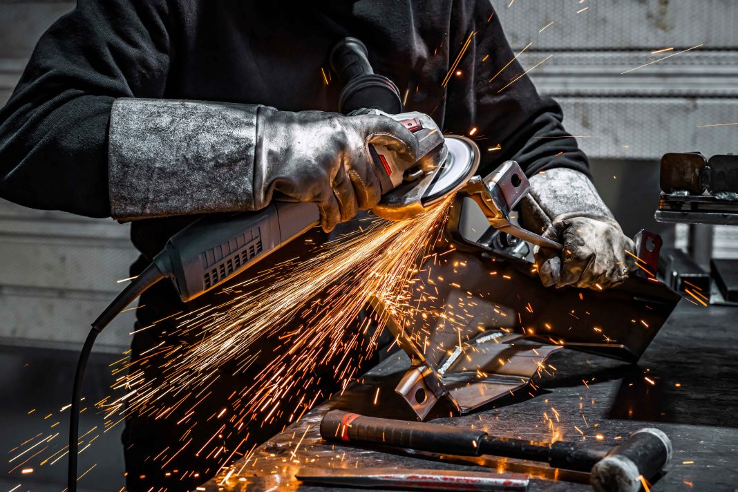 View worker grinding piece metal.